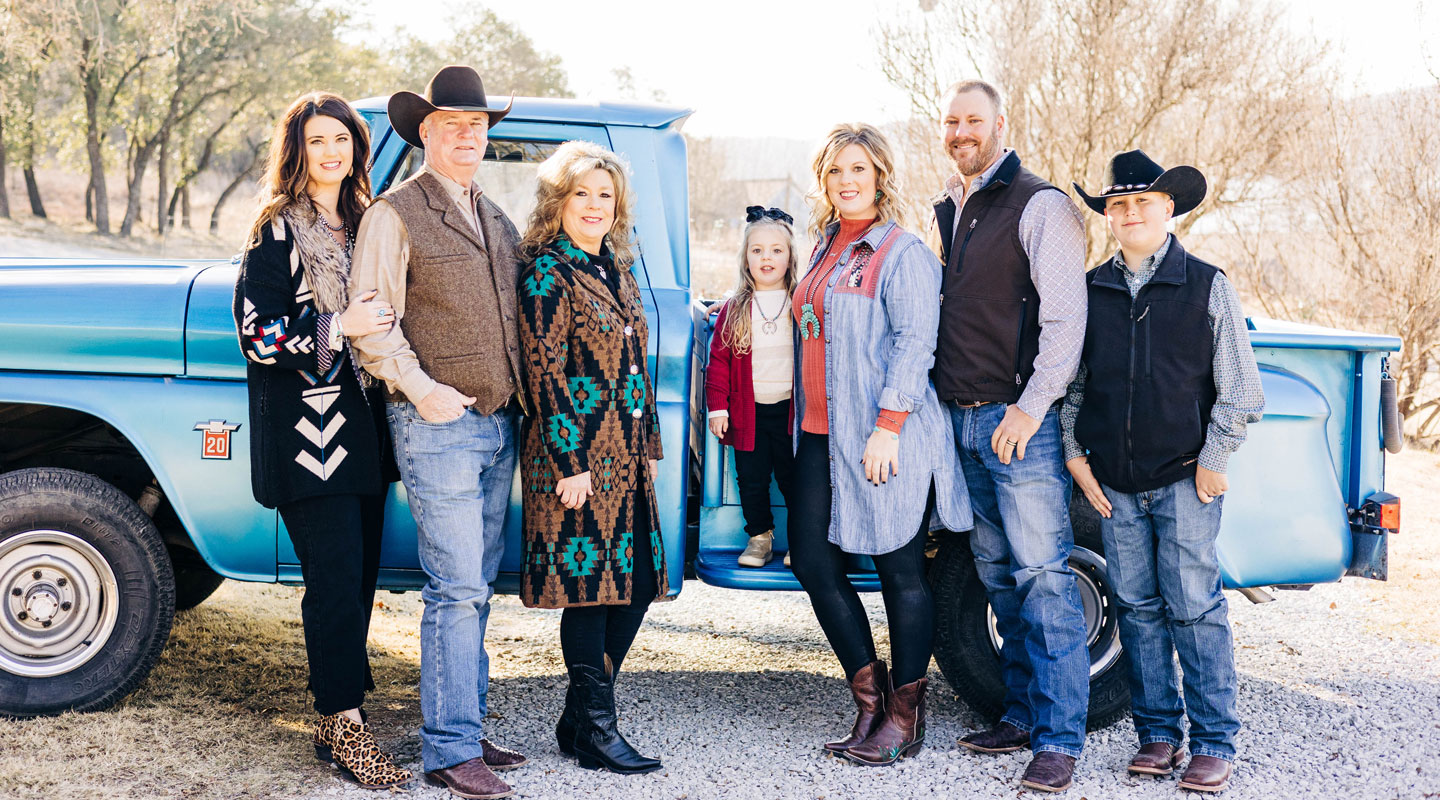 A group photo of Shelbi’s family posing next to a turquoise colored truck, posing and smiling.
